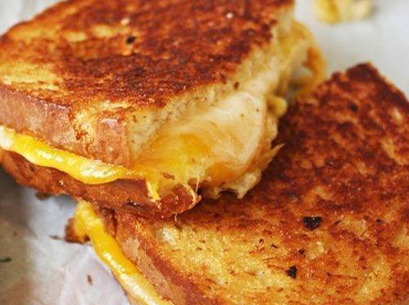 Grilled cheese sandwich cut in half and served on a white background